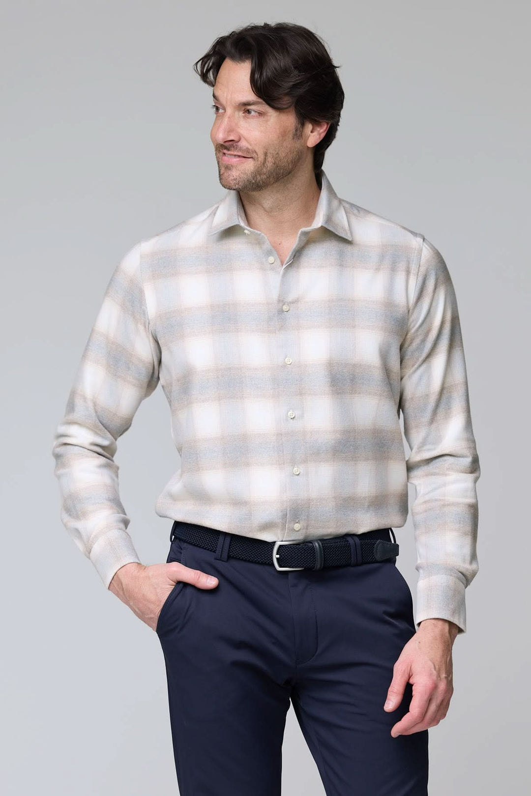 Homme portant une chemise à carreaux doux en flanelle, col semi-rigide, boutons nacrés, tenue élégante et décontractée, fond gris clair.
