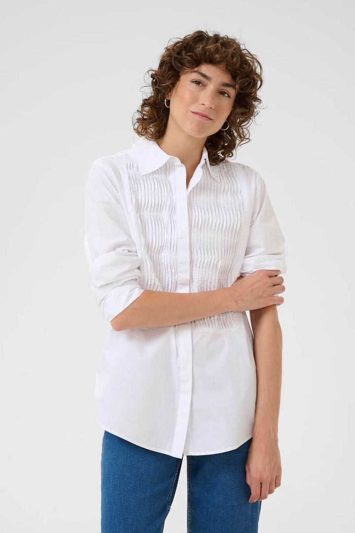 Femme portant une chemise classique avec plis nervurés, coupe droite et col chemise, tenue polyvalente pour un look élégant ou décontracté.