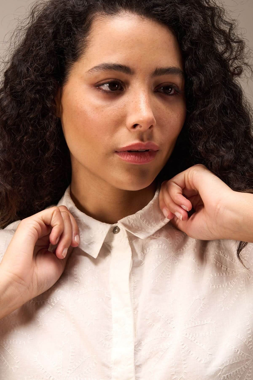 Modèle portant une chemise courte à col classique avec broderie délicate sur fond neutre.
