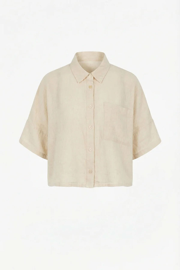 Chemise courte en lin à coupe ample avec col classique et poche plaquée, idéale pour un look moderne et confortable.