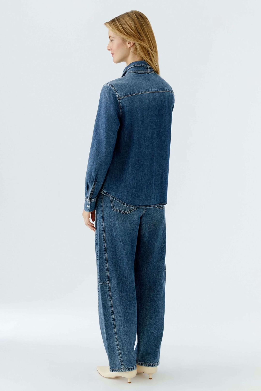 Vue arrière d'une femme portant une chemise en denim avec nœud amovible, style décontracté et moderne.