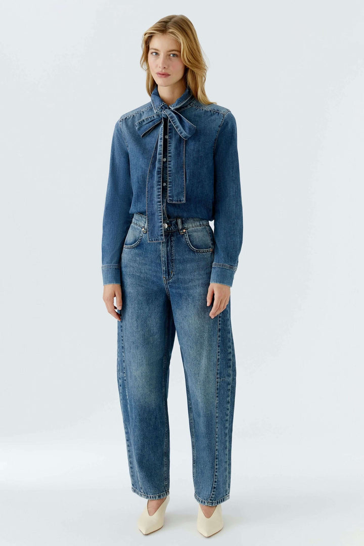 Chemise en denim avec nœud amovible portée avec jean, élégance moderne et féminine.