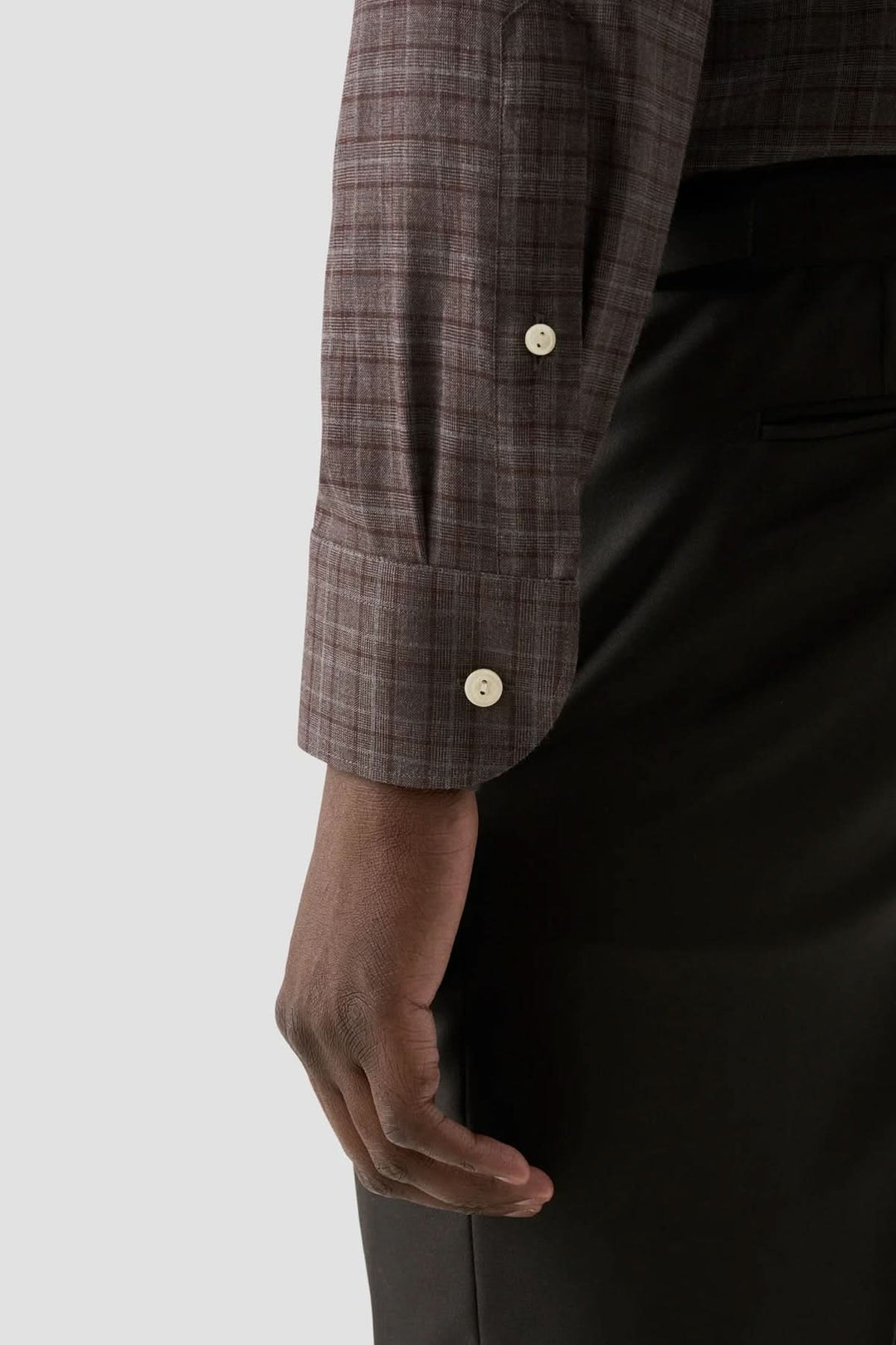 Détail de la manche d'une chemise en flanelle à carreaux, mettant en valeur le tissu et les boutons élégants.