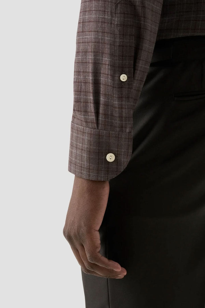 Détail de la manche d'une chemise en flanelle à carreaux, mettant en valeur le tissu et les boutons élégants.