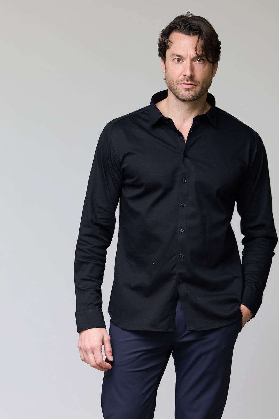Homme portant une chemise en jersey extensible noire à manches longues, coupe ajustée, idéale pour un look moderne et polyvalent.