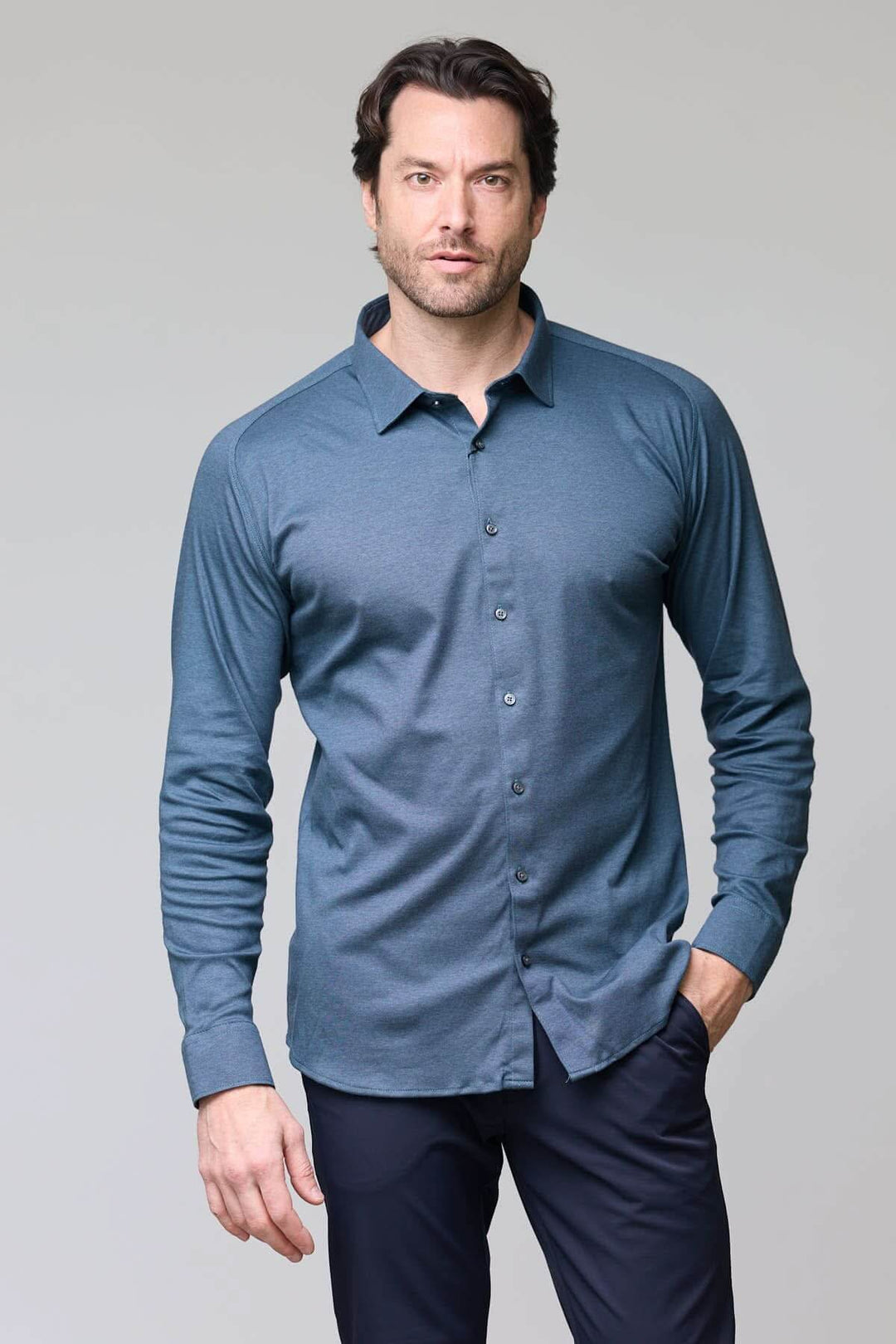Homme portant une chemise en jersey extensible, manches longues, coupe ajustée, col structuré, idéale pour le travail et moments décontractés.