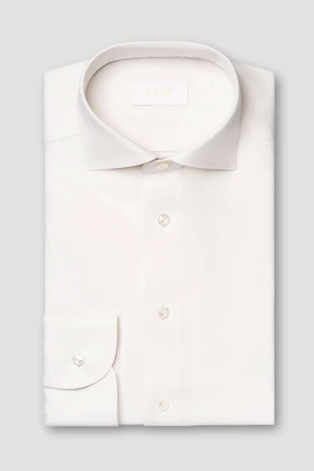 Chemise blanche en laine mérinos, col doux et boutons en nacre, élégante et confortable.