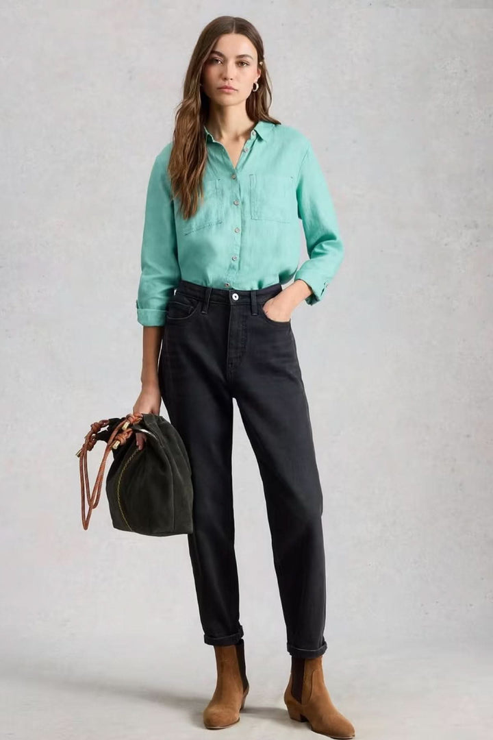 Femme portant la chemise en lin Sophie avec un look décontracté et moderne, idéal pour le quotidien. Pantalon noir et bottines marron.