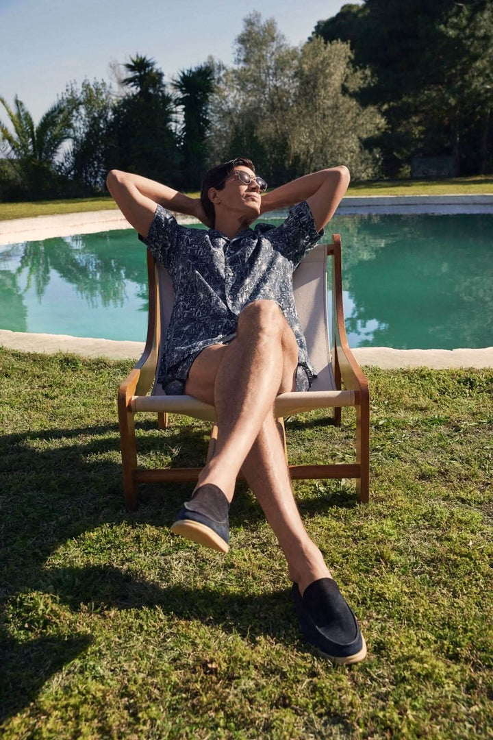 Homme détendu en chemise à imprimé tropical, assis sur une chaise près d&