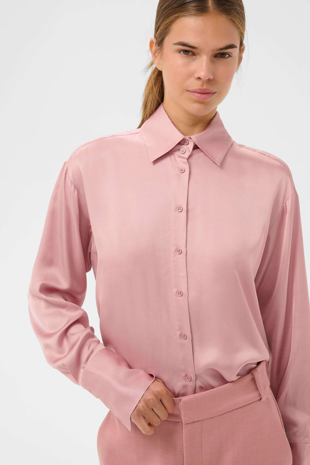 Femme portant la chemise fluide Pauline rose avec un col classique et une coupe droite élégante, symbolisant le style moderne et polyvalent.