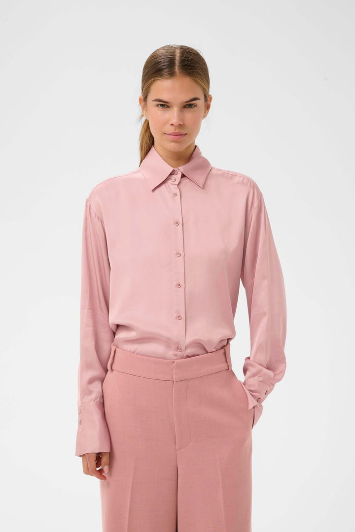 Femme portant la Chemise fluide Pauline rose, coupe droite et fluide avec col classique, idéale pour un style élégant et polyvalent.