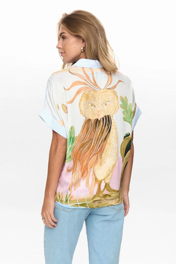 Femme portant chemise fluide à rayures avec imprimé artistique au dos, manches courtes et coupe ample, dos visible.