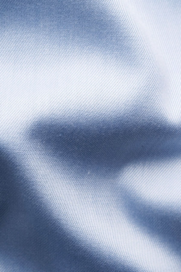 Gros plan sur un tissu en coton bleu, mettant en valeur sa texture douce et raffinée.
