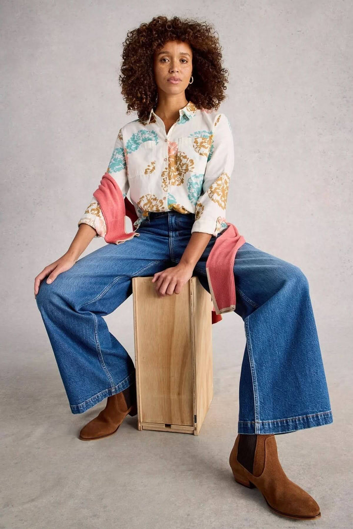 Femme portant une chemise imprimée coupe décontractée Sophie, style casual chic avec jeans évasés et bottines marron.