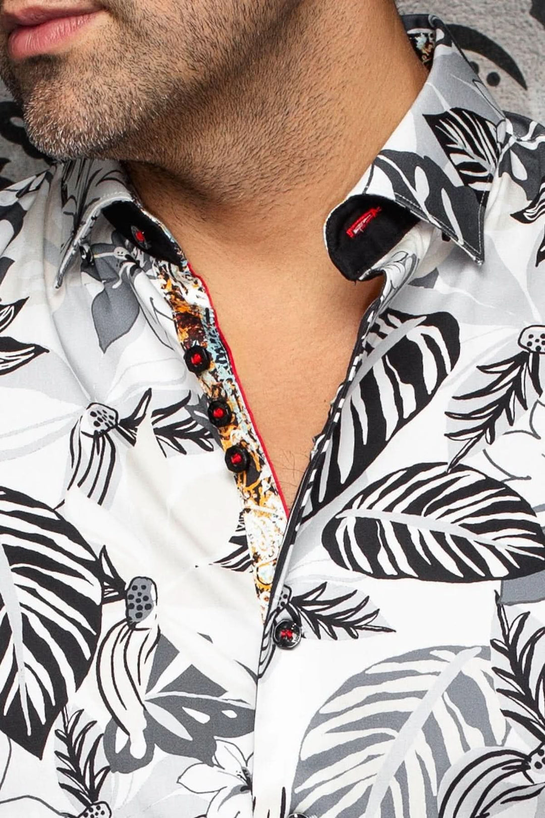 Chemise imprimée à manches courtes avec un motif audacieux de feuilles noires et blanches, col classique et boutonnière visible.