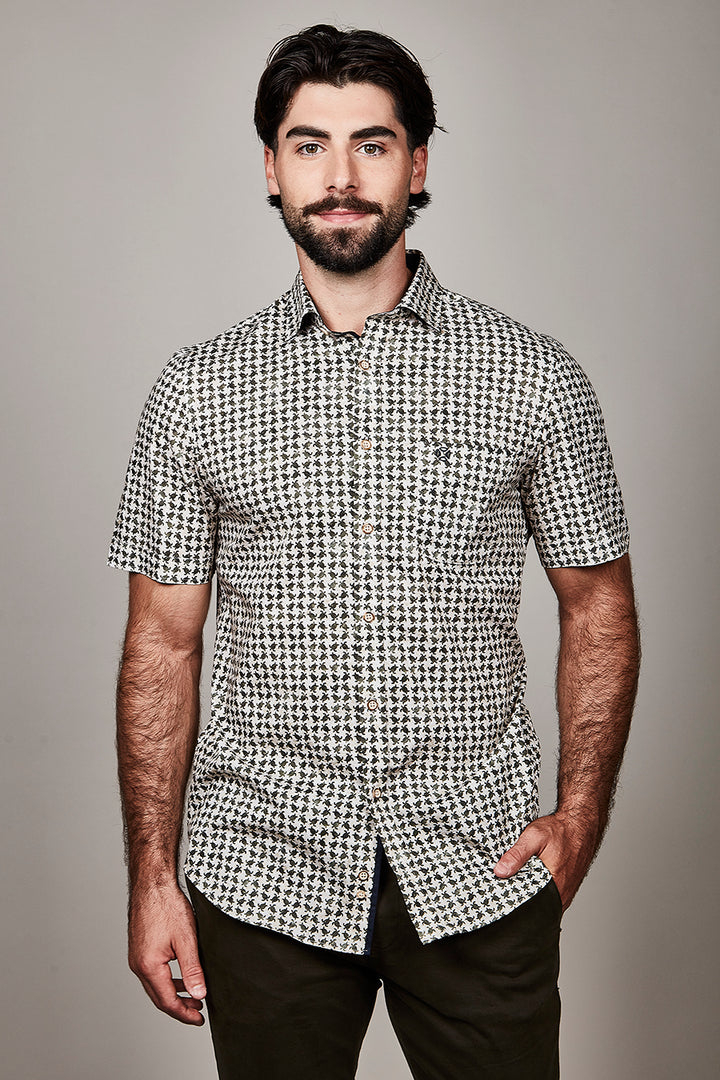 Homme portant une chemise à manches courtes à motif distinctif, style moderne et élégant pour un look soigné quotidien.