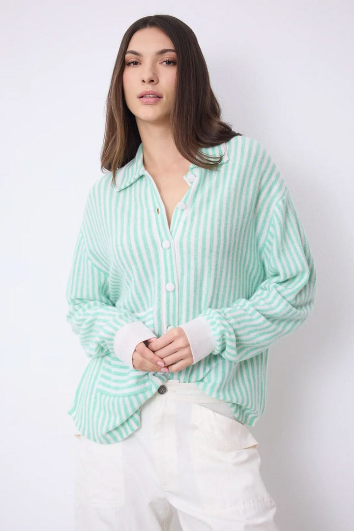 Femme portant une chemise oversize en cachemire à rayures vertes et blanches, élégante et confortable. Décris moi le produit en français.