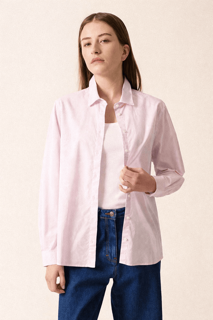 Une femme portant la chemise rayée LENA en coton, coupe droite, col chemisier, manches longues, associée à un jean pour un style décontracté.