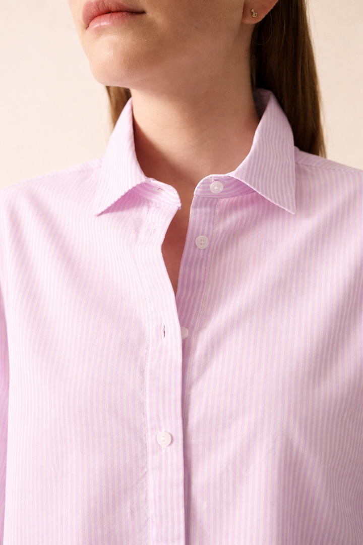 Chemise rayée LENA en coton rose clair avec col chemisier et manches longues, portée pour un look élégant et confortable.