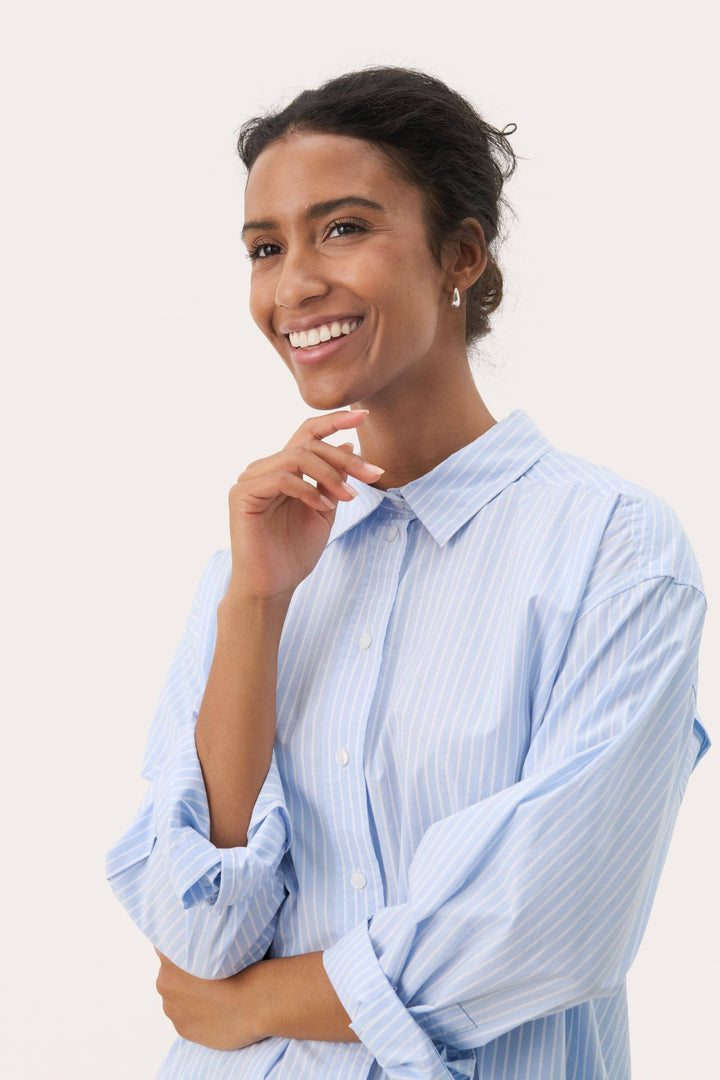 Femme portant une chemise rayée Savanna ample avec manches longues roulottées, parfaite pour un style chic et décontracté.