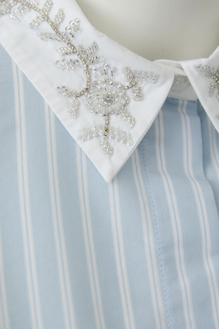 Chemise rayée à col brodé avec motifs délicats et broderies élégantes, vue de près pour son design chic et féminin.