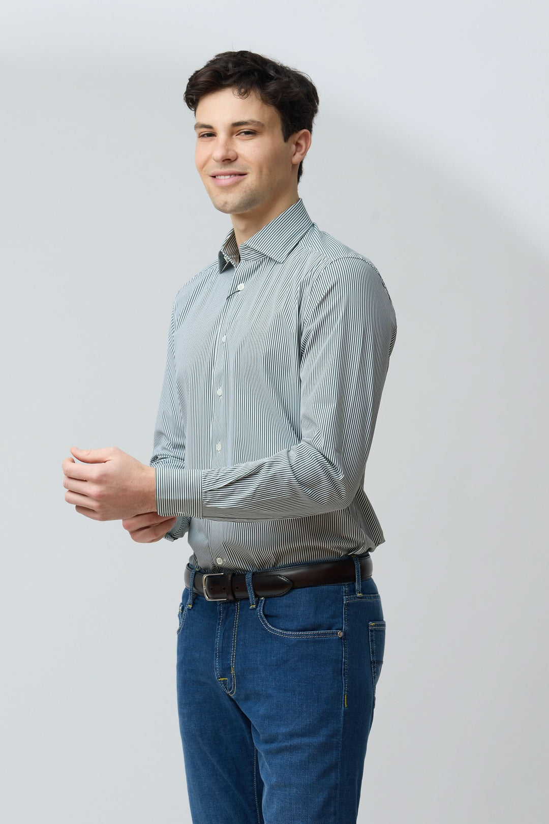 Homme portant une chemise à rayures vertes fines, coupe ajustée, avec jean, style moderne et confort, idéal pour différentes occasions.