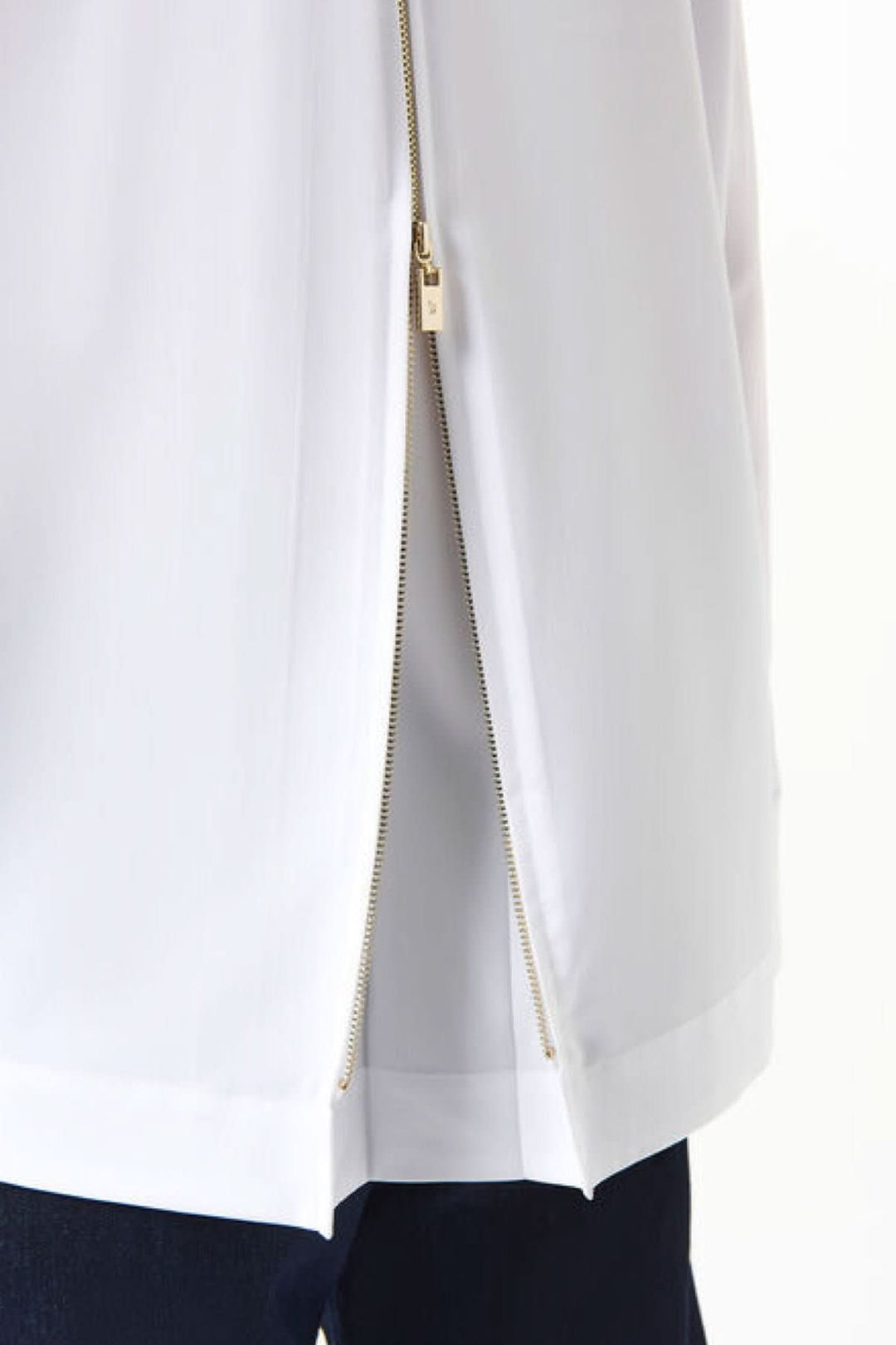 Détail d'un chemisier blanc avec zip doré sur le côté, alliant élégance et modernité.