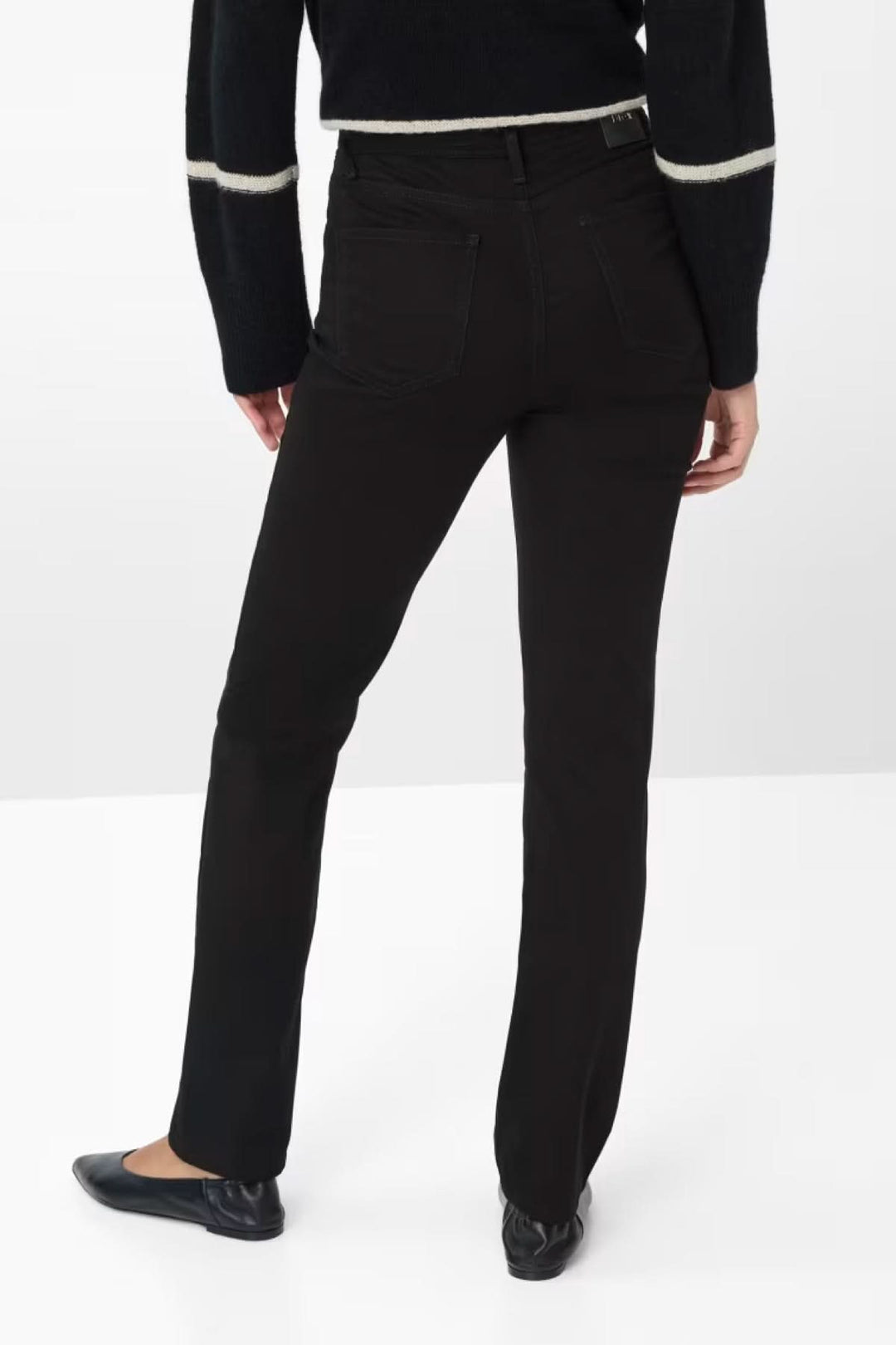 Pantalon chino noir avec coupe ajustée, vue arrière, porté avec un pull élégant et des ballerines.
