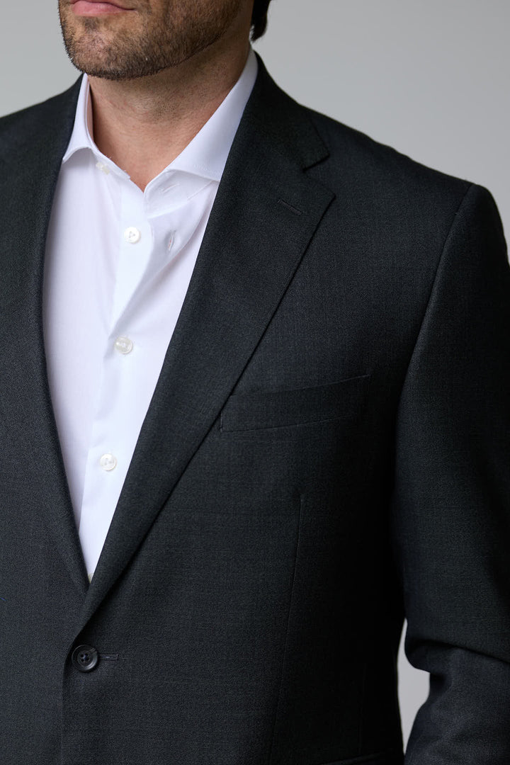 Homme portant un complet classique deux pièces élégant en tissu structuré avec veste à deux boutons et revers classiques.