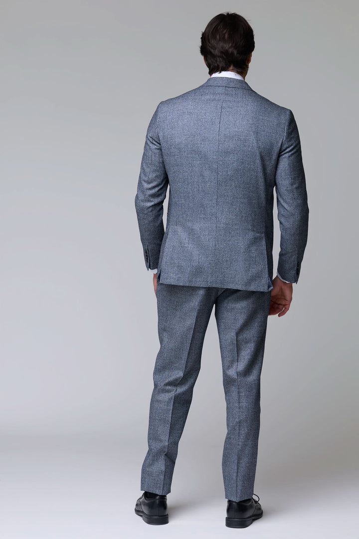 Homme portant un complet à motif micro-carreaux, vue de dos, montrant la coupe ajustée et le motif discret mais sophistiqué.