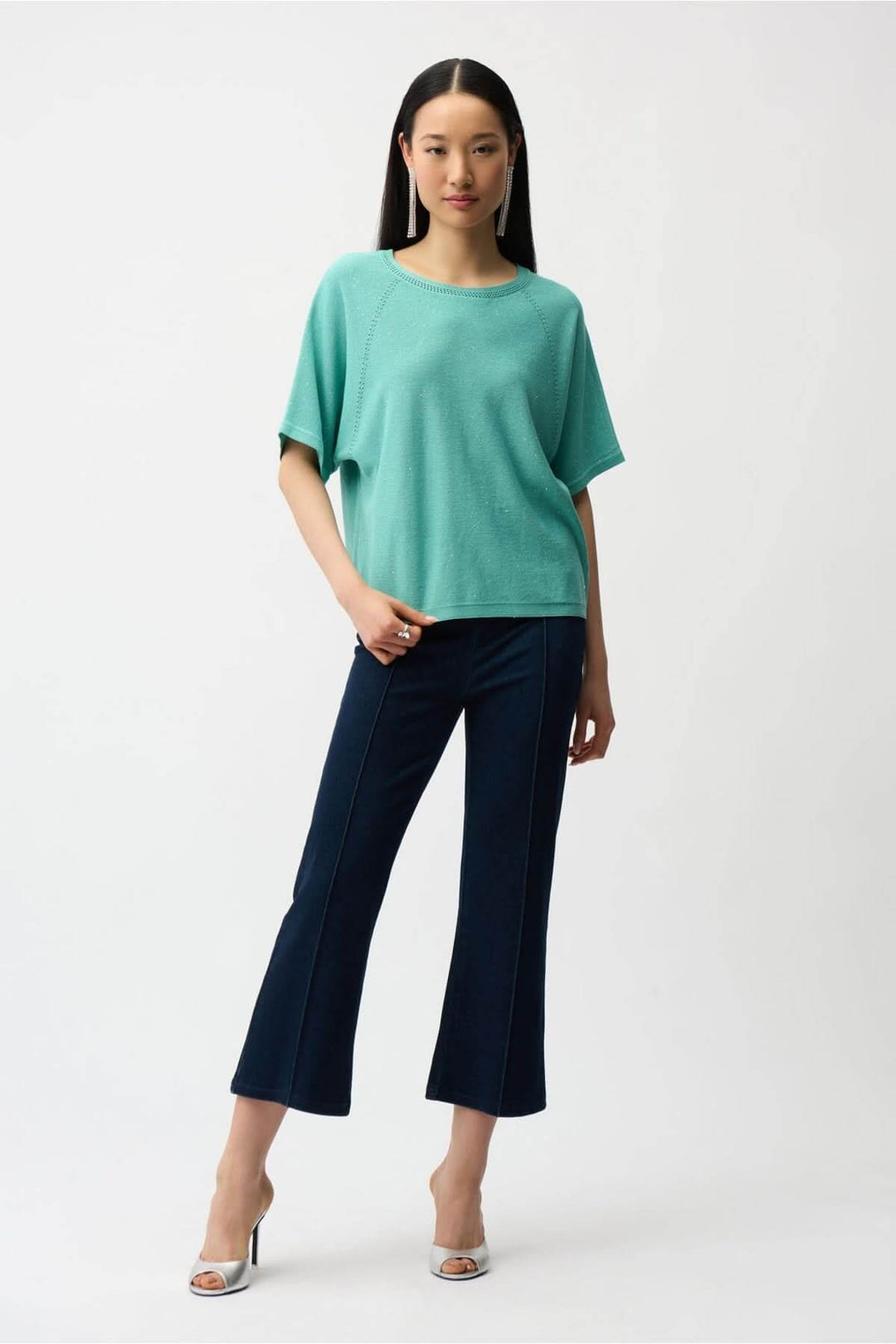 Femme portant un denim évasé raccourci à taille haute avec un haut vert, présentant une silhouette moderne et élégante. Décris moi le produit en français.