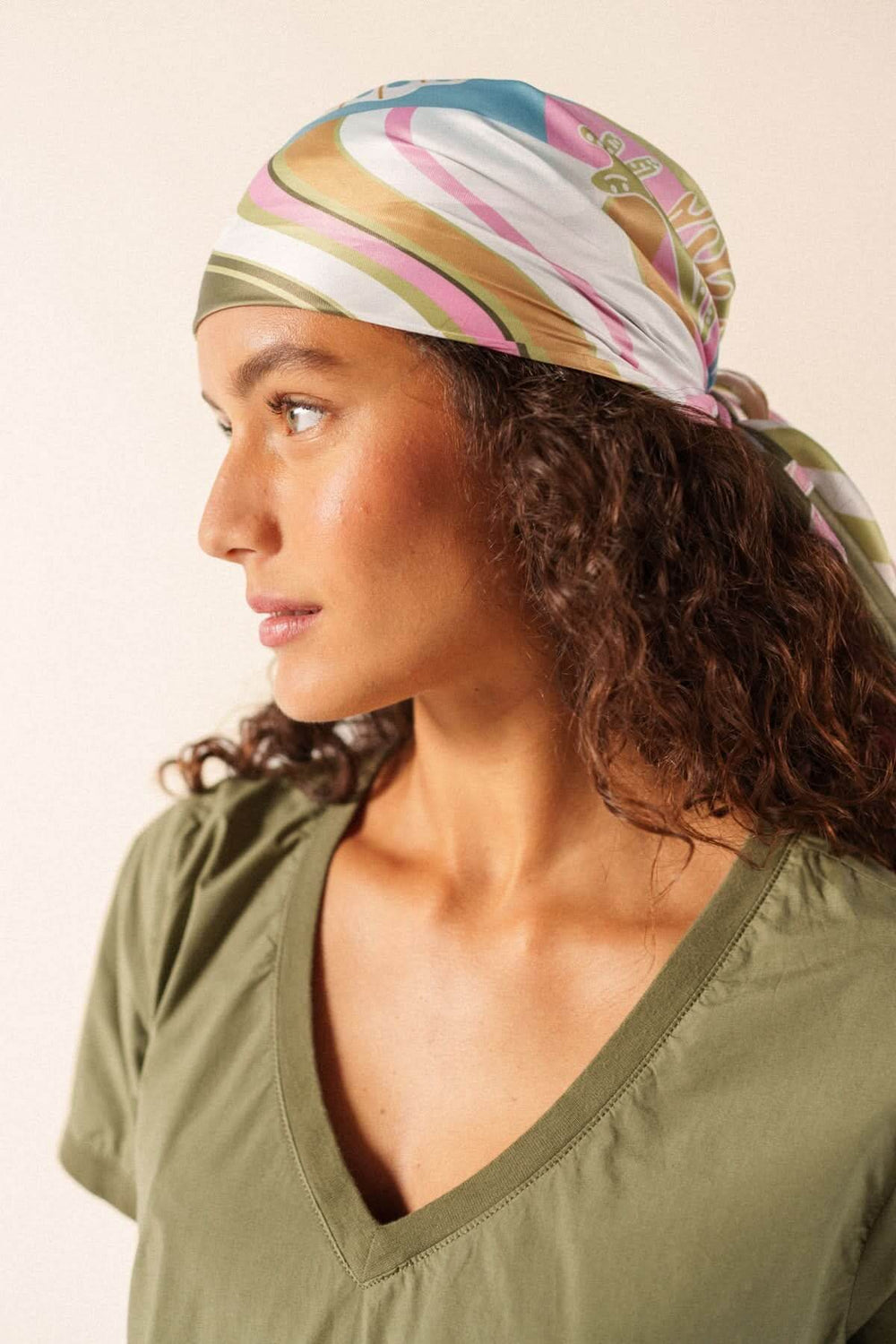 Femme portant le Foulard CARRE FOND MARIN avec motif graphique, noué dans les cheveux pour un style élégant.