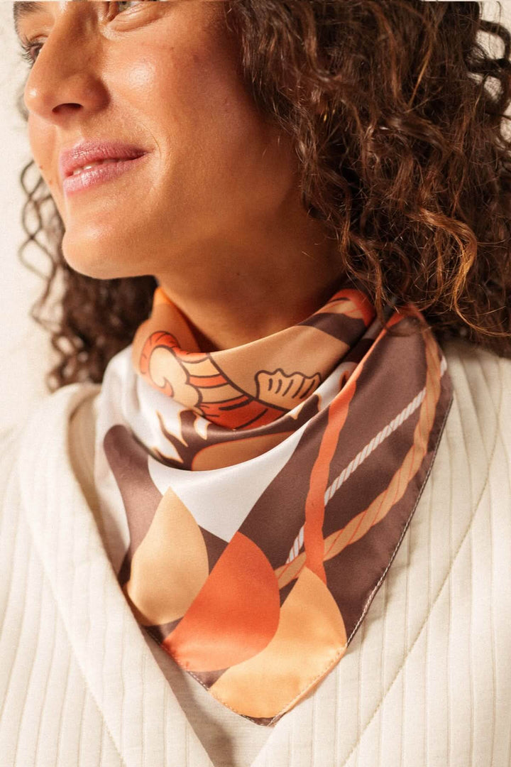 Foulard CARRE FOND MARIN avec motif graphique porté autour du cou pour un style élégant et raffiné.