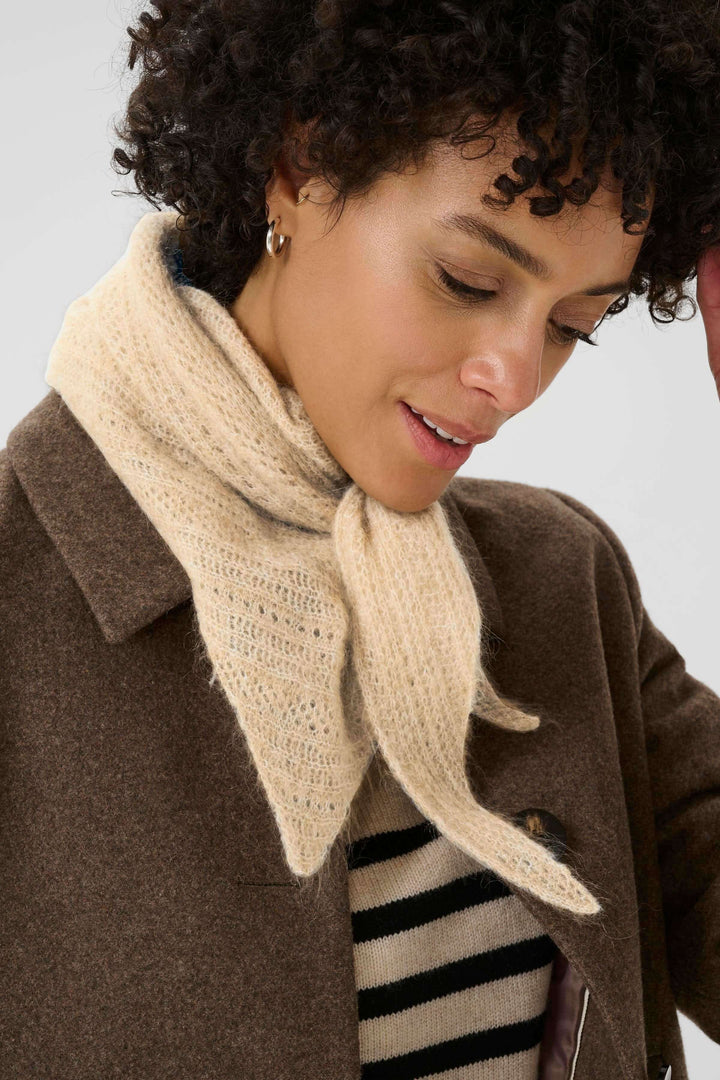 Foulard Sizze en tricot léger porté croisé sous un manteau pour un look moderne, offrant douceur et raffinement discret.