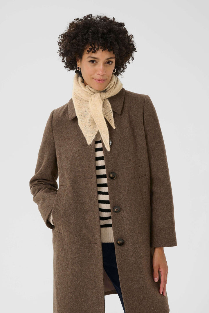 Foulard Sizze en tricot léger porté sous un manteau marron pour un look moderne et minimaliste.