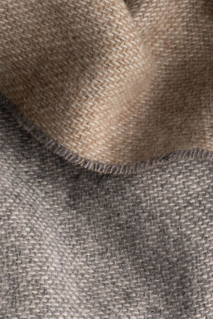 Texture of a luxurious cashmere scarf in soft beige and gray shades, perfect for autumn style.