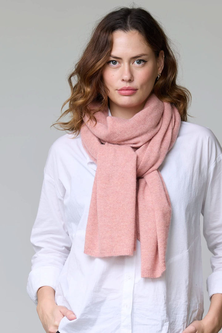 Foulard en laine rose porté par une femme, apportant confort et élégance, idéal pour les tenues d'automne et d'hiver.