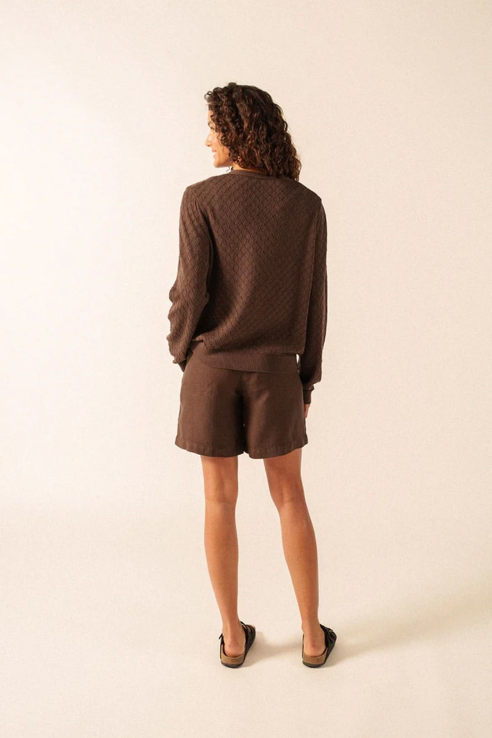 Vue arrière du Gilet Braga en maille texturée marron, coupe fluide et élégante, porté par une femme avec short.