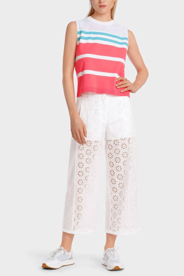 Haut en mèche coloré avec rayures, associé à un pantalon blanc en dentelle, style sportif.