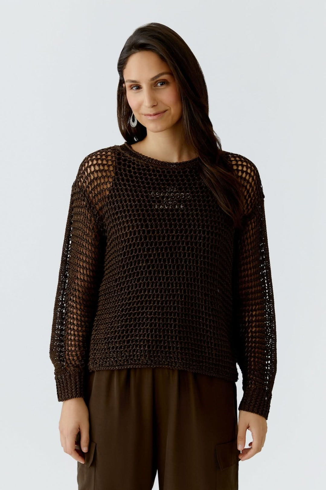 Femme portant un haut coupe moderne essentiel en maille marron, manche longue, design élégant et fluide.