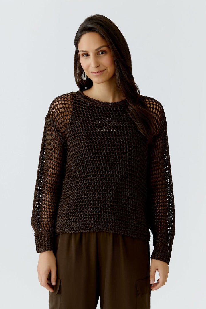 Femme portant un haut coupe moderne essentiel en maille marron, manche longue, design élégant et fluide.