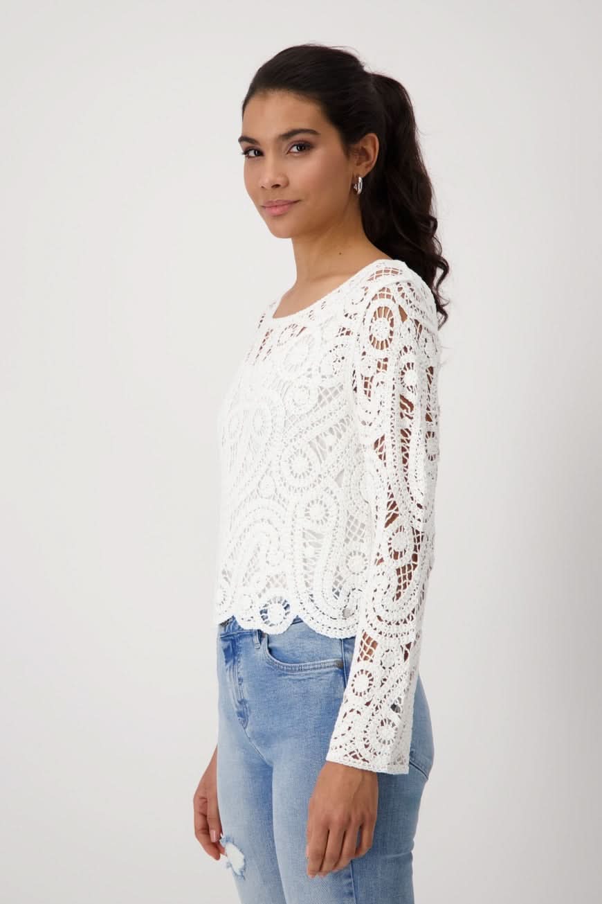 Chandail en crochet blanc avec col rond et manches longues, style chic, porté avec un jean.