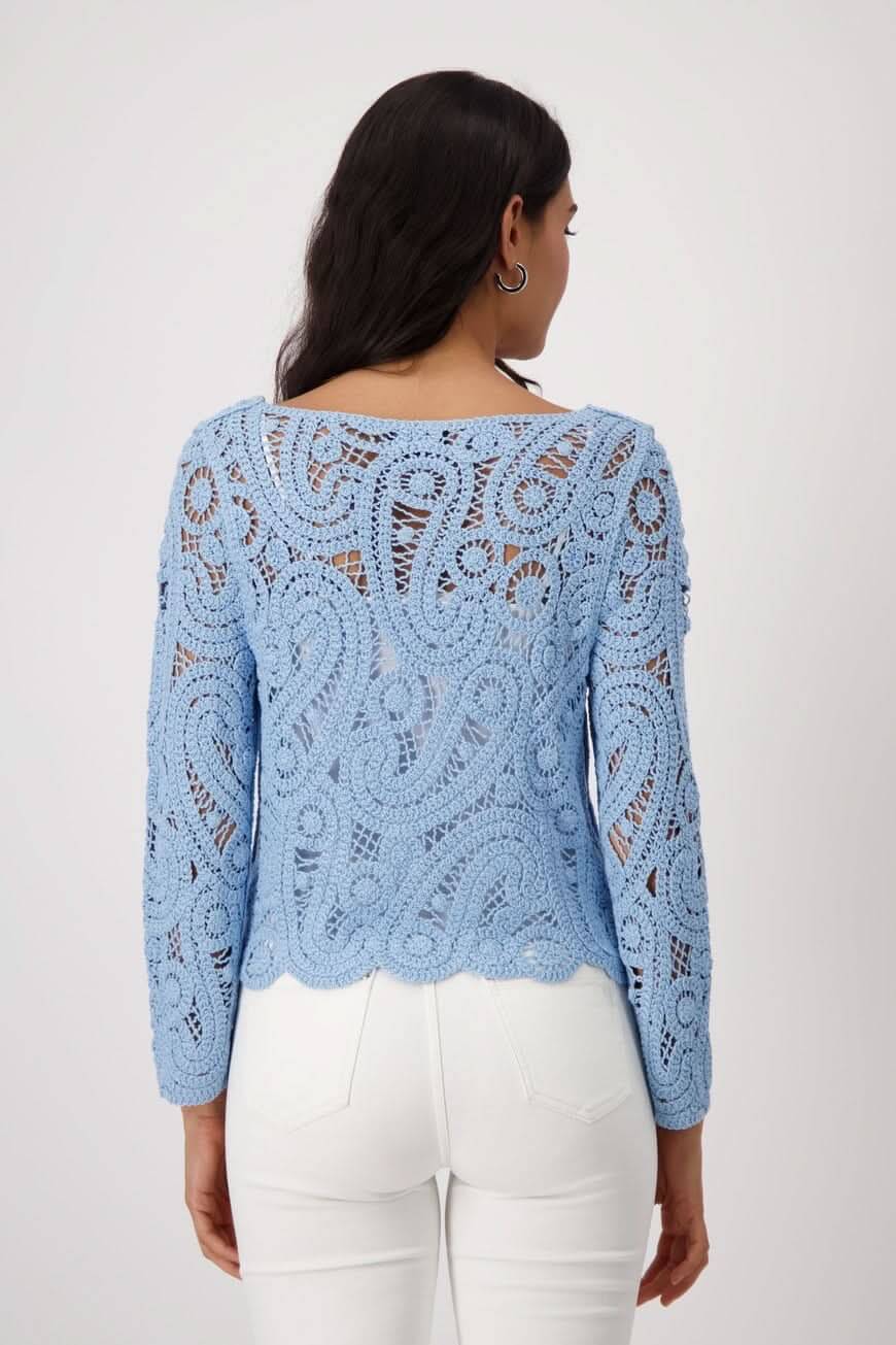 Chandail en crochet bleu avec motif délicat, coupe régulière, porté avec un pantalon blanc.