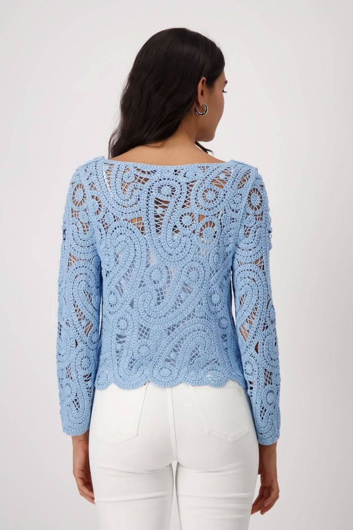 Chandail en crochet bleu avec motif délicat, coupe régulière, porté avec un pantalon blanc.