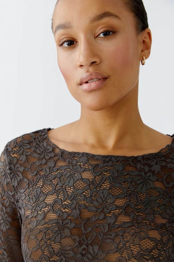 Haut en dentelle florale avec manches longues et encolure bateau, portés par un mannequin. Élégant et moderne pour un look sophistiqué.