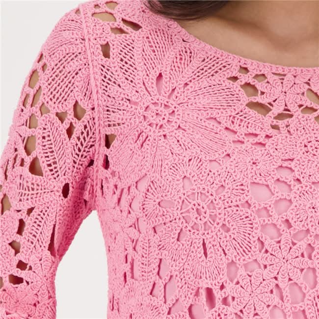 Haut en tricot ajouré rose avec motif floral délicat, encolure ronde dégagée, accentuant la silhouette pour un style féminin moderne.