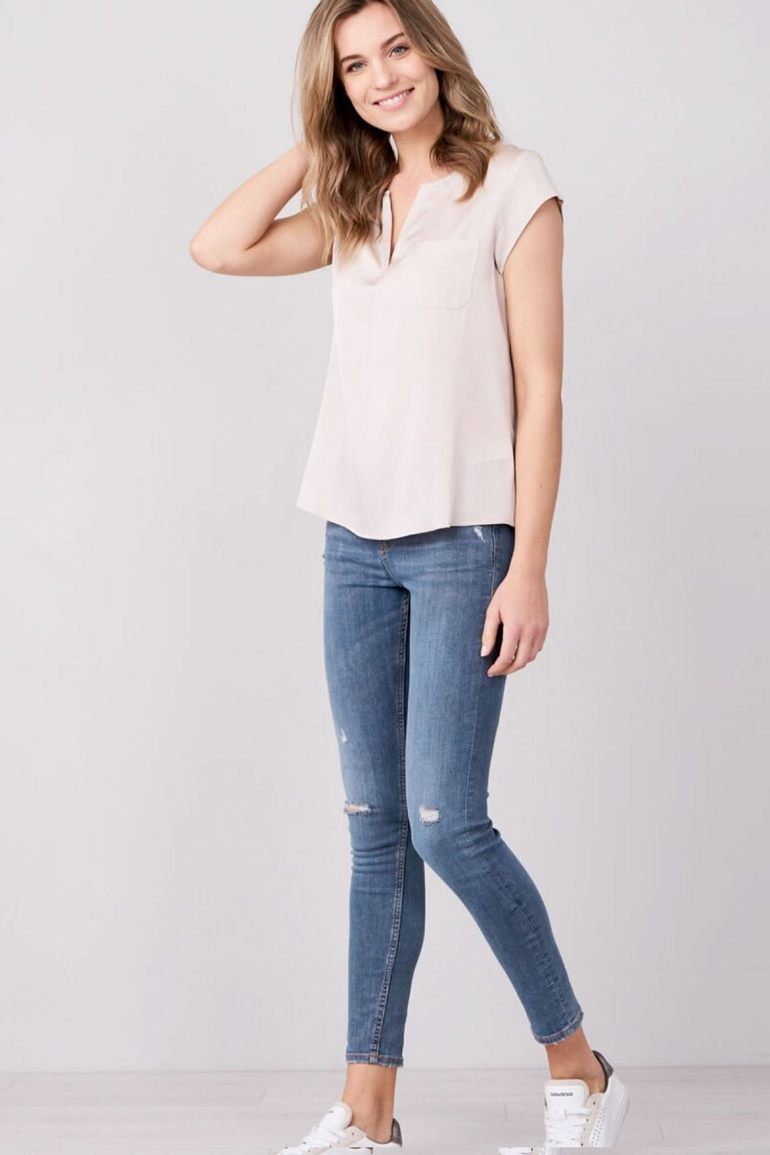 Femme portant un haut fluide col fendu manches courtes, style élégant et décontracté.