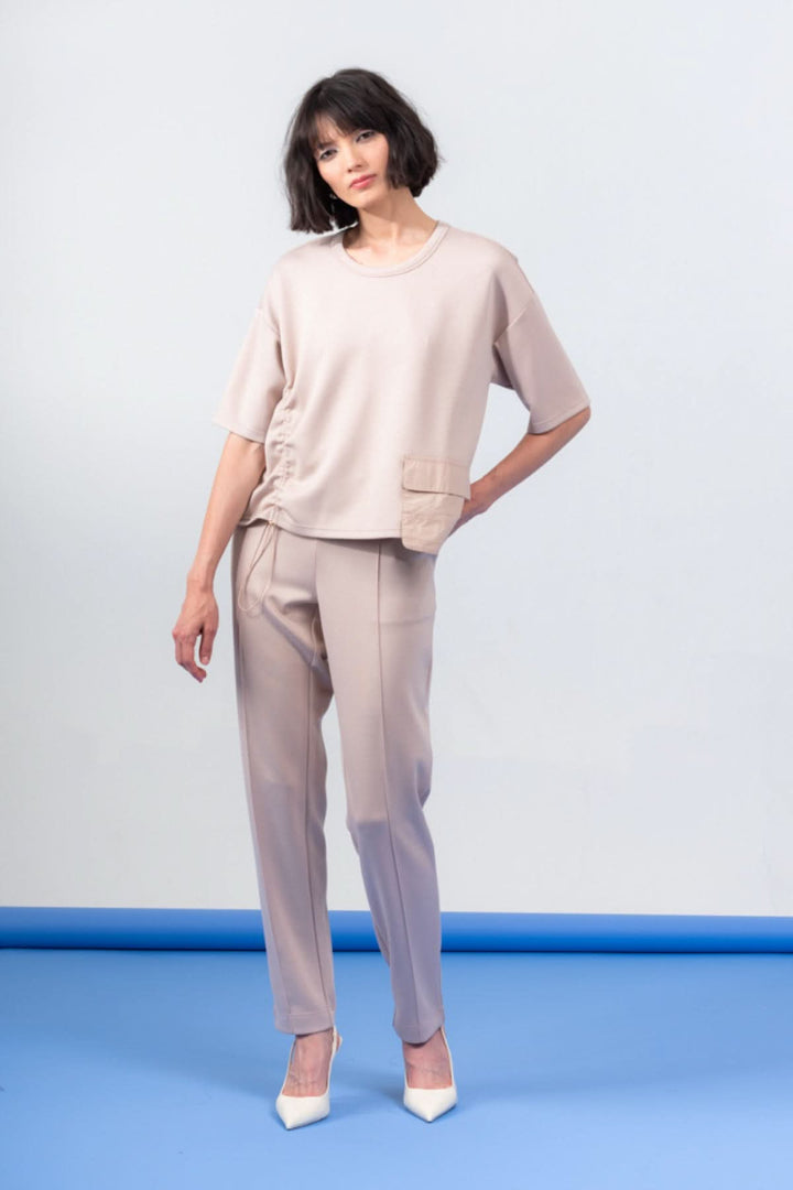 Haut à manches courtes oversize avec encolure ronde et poche, porté avec un pantalon beige élégant.