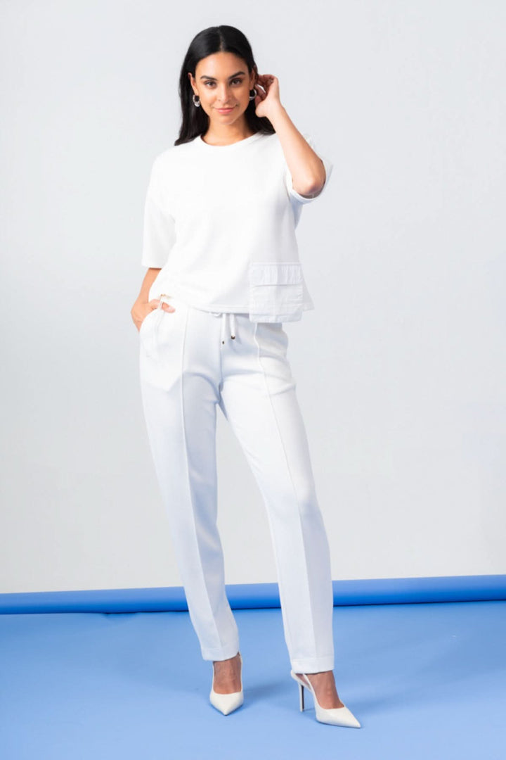 Femme portant un haut à manches courtes oversize blanc avec un pantalon élégant et des talons blancs.