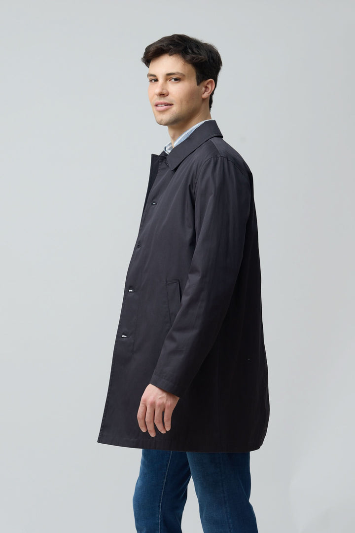 Homme portant un imperméable en gabardine de coton noir, tenue urbaine élégante et fonctionnelle.